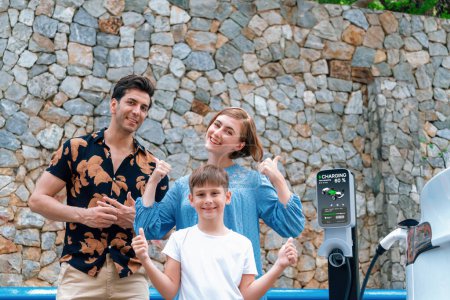 Photo for Family road trip vacation with electric vehicle, lovely family recharge EV car with green and clean energy. Stone seawall background and eco friendly car travel for sustainable environment. Perpetual - Royalty Free Image