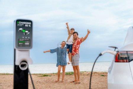 Photo for Family vacation trip traveling by the beach with eco-friendly electric car, lovely and cheerful family charging EV car battery on the seascape with green and sustainable energy. Perpetual - Royalty Free Image