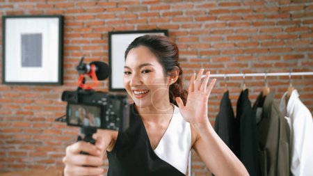 Photo for Woman influencer shoot live streaming vlog video review clothes social media or blog. Happy young girl with apparel vivancy studio lighting for marketing recording session broadcasting online. - Royalty Free Image
