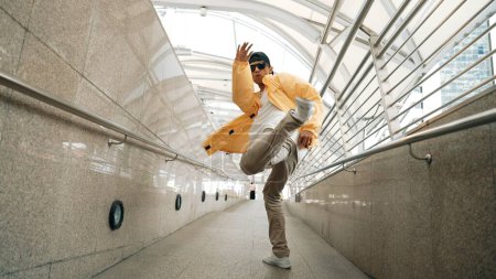 Photo for Skilled happy asian hipster walking while dancing in narrow corridor. Close up of break dancer practicing break dance performance. Professional man moving to music. Outdoor sport 2024. Sprightly. - Royalty Free Image