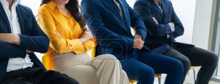 Téléchargez les photos : Les candidats à la diversité assis en attendant l'entrevue d'emploi avec le bras croisé en vue latérale. Image recadrée section basse de gens d'affaires souriant avec confiance. Salle d'attente moderne. Propriété intellectuelle. - en image libre de droit