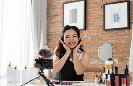 Téléchargez les photos : Asian Woman influenceur shoot live streaming vlog video review makeup uttermost réseaux sociaux ou blog. Heureuse jeune fille avec éclairage de studio cosmétique pour la diffusion de session d'enregistrement marketing en ligne - en image libre de droit