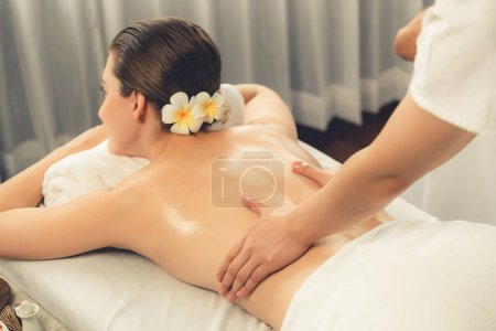 Téléchargez les photos : Femme caucasienne client appréciant relaxant massage spa anti-stress et dorloter avec la beauté loisirs de la peau dans la lumière du jour salon spa ambiant au complexe de luxe ou hôtel. Tranquillité - en image libre de droit