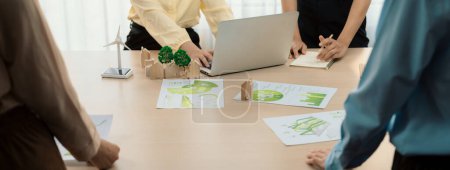Photo for Wooden block represented green city and wind mill represented renewable energy was placed at center of green business meeting table with environmental document. Green business concept. Delineation. - Royalty Free Image