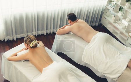Téléchargez les photos : Vue de dessus client couple caucasien profiter relaxant massage spa anti-stress et dorloter avec la beauté de loisirs de la peau dans la lumière du jour salon spa ambiant au complexe de luxe ou hôtel. Tranquillité - en image libre de droit