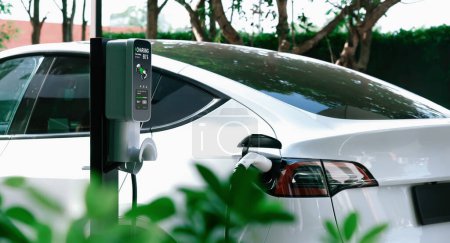Chargement de voiture électrique EV dans le vert jardin extérieur durable de la ville en été. Style de vie urbain durable par vert propre énergie rechargeable des véhicules électriques BEV à l'intérieur