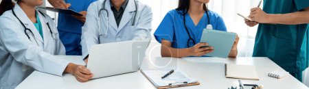 Photo for Professional various team of medical working and planning medical treatment at hospital table together. Teamwork lead to successful illness and sickness treatment. Panorama Rigid - Royalty Free Image