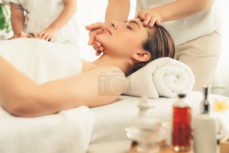 Photo for Caucasian couple enjoying relaxing anti-stress head massage and pampering facial beauty skin recreation leisure in dayspa modern light ambient at luxury resort or hotel spa salon. Quiescent - Royalty Free Image
