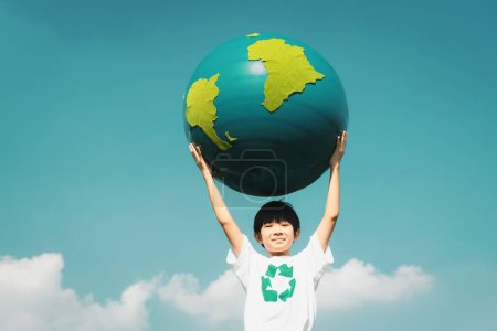 Foto de Joven chico asiático sosteniendo el planeta Tierra globo en el cielo y el fondo nuboso como el día de la Tierra para salvar a este planeta con el principio ESG y la energía amigable con el medio ambiente para un futuro más brillante. Gyre. - Imagen libre de derechos