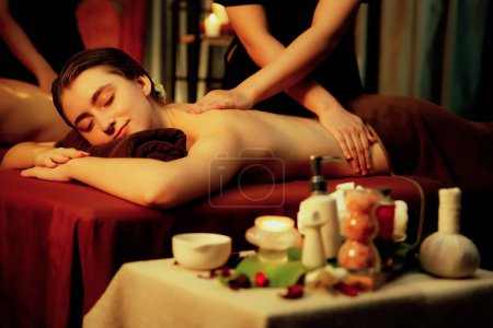Téléchargez les photos : Couple caucasien client appréciant relaxant massage spa anti-stress et dorloter avec beauté loisirs de la peau dans la bougie chaude éclairage spa salon d'ambiance à la station de luxe ou hôtel. Tranquillité - en image libre de droit