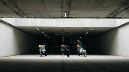 Panorama shot of hipster group dance together while perform b-boy dance. Street dancer team moving to hip hop music while doing freeze pose. Break dance, street dance. Outdoor sport 2024. Sprightly.