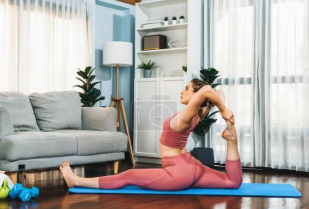 Photo for Flexible and dexterity woman in sportswear doing yoga position in meditation posture on exercising mat at home. Healthy gaiety home yoga lifestyle with peaceful mind and serenity. - Royalty Free Image