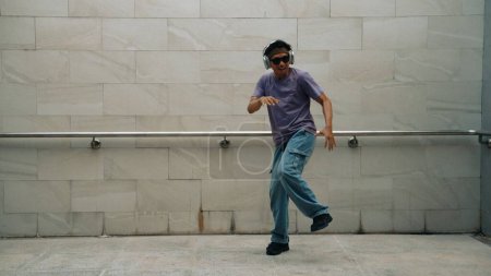 Photo for Motion shot of hipster listen music while move or dance to music at dancing room. Attractive street dancer practice b-boy footstep. Freestyle dance concept. Lifestyle. Outdoor sport 2024. Sprightly. - Royalty Free Image
