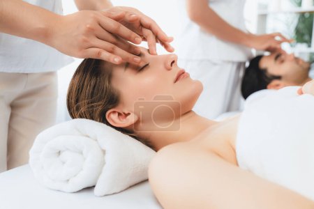 Photo for Caucasian couple enjoying relaxing anti-stress head massage and pampering facial beauty skin recreation leisure in dayspa modern light ambient at luxury resort or hotel spa salon. Quiescent - Royalty Free Image