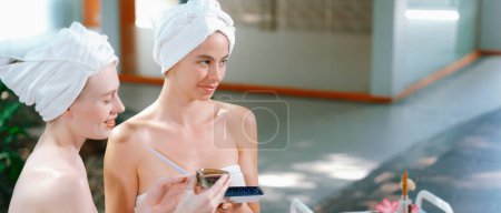 Photo for A portrait of two beautiful caucasian woman in white towel using homemade facial mask rounded by peaceful natural environment at outdoor. Healthy and beauty concept. Blurring background. Tranquility. - Royalty Free Image
