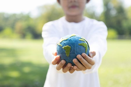 Photo for Young asian boy holding planet Earth globe at natural park background as Earth day to save this planet with ESG principle and environment friendly energy for brighter future. Gyre - Royalty Free Image