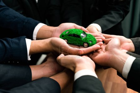 Téléchargez les photos : Les gens d'affaires détenant un modèle de voiture électrique en tant que partenariat de synergie d'entreprise s'unissent et prennent des mesures pour utiliser l'éco-transport afin de réduire les émissions de CO2 pour un avenir durable et plus vert. Charmante. - en image libre de droit