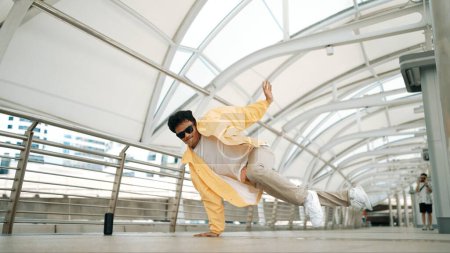 Photo for Handsome happy asian hipster dancing while using head spin at corridor. Break dancer or choreographer looking at camera while perform street dancing. Freestyle song. Outdoor sport 2024. Sprightly. - Royalty Free Image