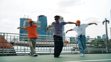 Photo for Group of skilled break dancer perform hip hop foot step together at rooftop with city or skyscraper view. Handsome hipster team moving to funky music at public place. Outdoor sport 2024. Sprightly. - Royalty Free Image