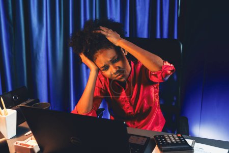 Foto de Trabajar mujer de negocios africana que sufre de dolor de cabeza con el trabajo en línea, sentado en la oficina en casa, analizando el plan de marketing para el objetivo. Concepto de estrés, tensión, sobre la expresión del pensamiento. Tastemaker. - Imagen libre de derechos