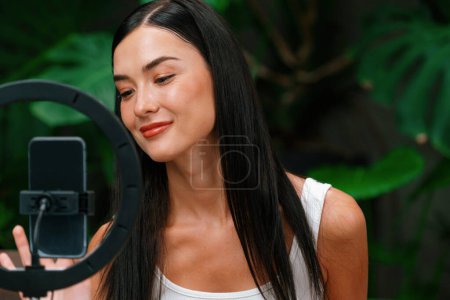 Photo for Young woman making natural beauty and cosmetic tutorial on green plant garden video content for social media. Beauty celebrity blogger showing how to beauty care to audience or followers. Blithe - Royalty Free Image