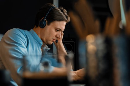 Photo for Call center consulting with customers on headphones on monitor in business paragraph with typing on pc with dynamic data marketing analysis planning at modern home office at night time. Pecuniary. - Royalty Free Image