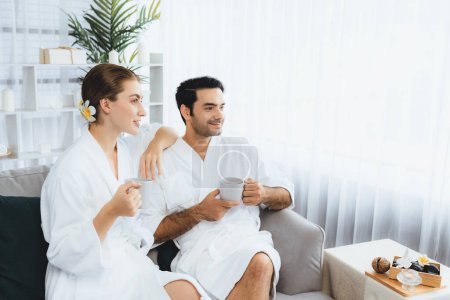 Photo for Beauty or body treatment spa salon vacation lifestyle concept with couple wearing bathrobe relaxing with drinks in luxurious hotel spa or resort room. Vacation and leisure relaxation. Quiescent - Royalty Free Image