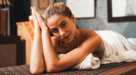 Photo for Portrait of beautiful caucasian woman in white towel woman lies on spa bed in front of warm wooden sauna cabinet with relaxation and peaceful at spa salon. Close up. A Side view. Tranquility. - Royalty Free Image