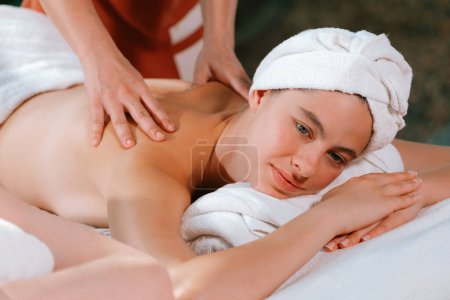 Téléchargez les photos : Belle jeune femme a reçu un massage du dos sur un lit de spa de masseuse professionnelle. Attrayant femelle se détend profondément par les mains habiles du massothérapeute. Entouré de nature. Tranquillité. - en image libre de droit