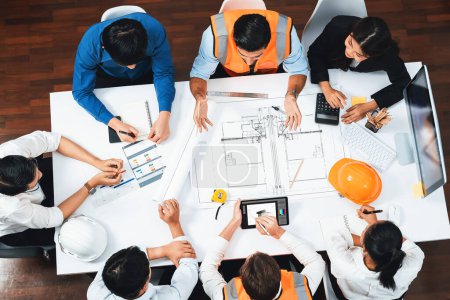 Photo for Top view banner of diverse group of civil engineer and client working together on architectural project, reviewing construction plan and building blueprint at meeting table. Prudent - Royalty Free Image