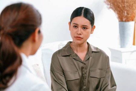 Photo for Sad PTSD woman patient in uttermost therapy for mental health with psychologist, depression or grief after life failure. Frustrated trauma young woman talking to a psychologist about emotion in office - Royalty Free Image