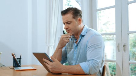 Photo for Businessman struggle to solve work problem from home using laptop, sitting on his desk at home office with stressed and frustrated expression, trying to figure out solution for problem. Synchronos - Royalty Free Image