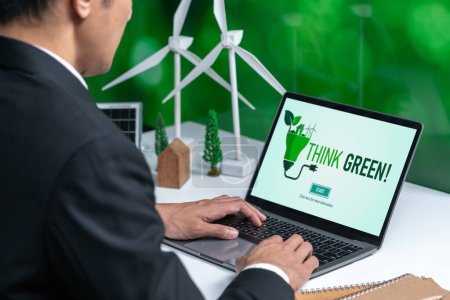 Empresario que trabaja en la oficina desarrollando un plan o proyecto sobre energía alternativa ecológica con tecnología de células solares en la pantalla del ordenador para un entorno más verde, aparte del esfuerzo de RSE. Gyre.