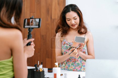 Photo for Asian Woman influencer shoot live streaming vlog video review makeup uttermost social media or blog. Happy young girl with cosmetics studio lighting for marketing recording session broadcasting online - Royalty Free Image