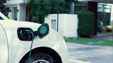 Photo for Electric car plugged in with home charging station to recharge battery by EV charger cable. Future innovative EV car and energy sustainability. Smart and futuristic home energy infrastructure. Peruse - Royalty Free Image