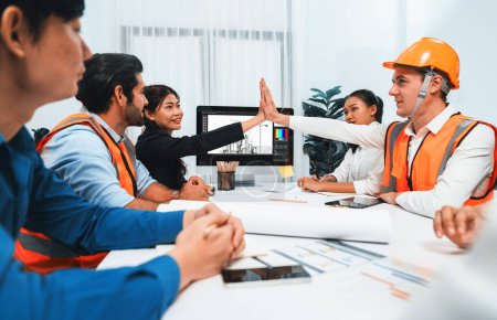 Photo for Diverse group of civil engineer and client celebrate and high five after make successful agreement on architectural project, reviewing construction plan and building blueprint at meeting table.Prudent - Royalty Free Image