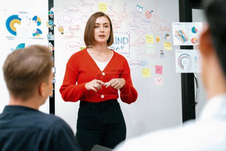 Professional attractive female leader presents creative marketing plan by using brainstorming mind mapping statistic graph and colorful sticky note at modern business meeting room. Immaculate.