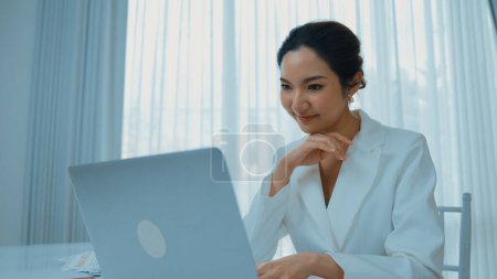 Foto de Joven empresaria sentada en el escritorio del espacio de trabajo usando un ordenador portátil para escribir contenido en línea en Internet o un secretario a distancia que trabaja desde casa. Vivancia - Imagen libre de derechos