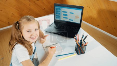 Photo for Top view of happy student thinking doing homework by using laptop screen display engineering coding program or programing system. Girl planing for web development while looking at camera. Erudition. - Royalty Free Image