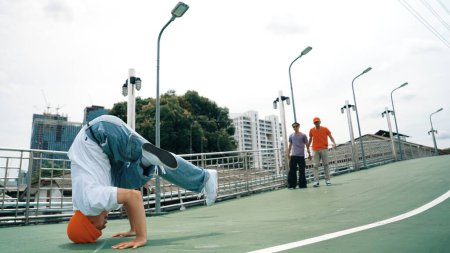 Photo for Professional hipster walking while doing freeze pose at bridge. Break dancer perform hip hop footstep surrounded by group of hipster cheering or encouraging friend. Outdoor sport 2024. Sprightly. - Royalty Free Image