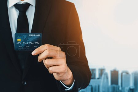 Téléchargez les photos : Portrait d'un homme d'affaires tenant une carte de crédit montrant la vue de face de la caméra en gros plan. Achats en ligne et concept de paiement sans espèces. uds - en image libre de droit