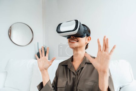 Téléchargez les photos : Jeune femme utilisant réalité virtuelle VR masque à la maison pour une expérience d'achat en ligne extrême. L'innovation VR en réalité virtuelle optimisée pour le divertissement numérique. - en image libre de droit