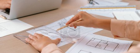 Photo for Professional architect drawing blueprint during meeting at modern architectural office on table with architectural document and stationary scatter around. Blurring background. Closeup. Delineation - Royalty Free Image