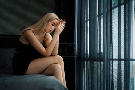 Photo for Young woman with critical depression and anxiety disorder from loneliness, mental sickness, or unwanted pregnancy, cuddling herself on dark bedroom. Overwhelming negative thought. Blithe - Royalty Free Image