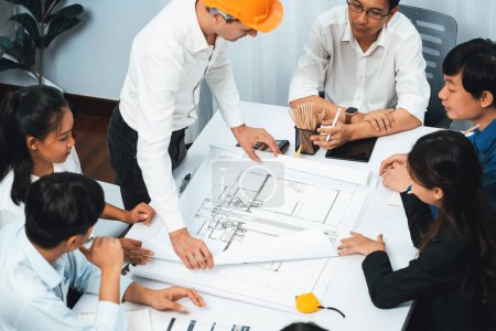 Photo for Diverse group of civil engineer and client working together on architectural project, reviewing construction plan and building blueprint at meeting table. Prudent - Royalty Free Image