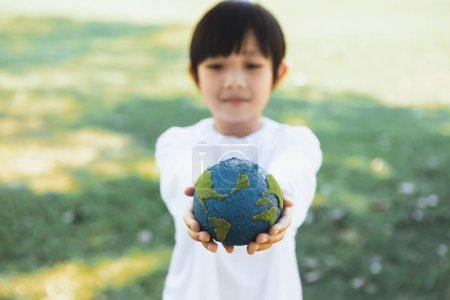 Foto de Joven chico asiático sosteniendo el planeta globo terráqueo en el fondo del parque natural como el día de la Tierra para salvar este planeta con el principio ESG y energía amigable con el medio ambiente para un futuro más brillante. Gyre. - Imagen libre de derechos