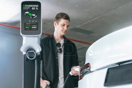 Photo for Young man travel with EV electric car to shopping center parking lot charging in downtown city showing urban sustainability lifestyle by green clean rechargeable energy of electric vehicle innards - Royalty Free Image