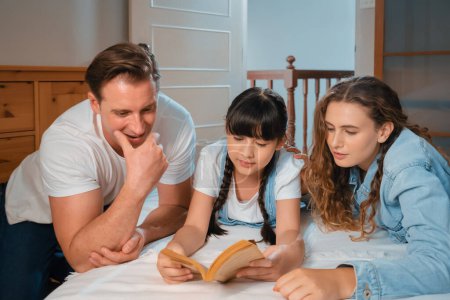 Photo for Bedtime story with childhood storytelling, mom and dad reading a fantasy book together to their little young girl in cozy and comfortable bedroom. Modern family happy time. Synchronos - Royalty Free Image