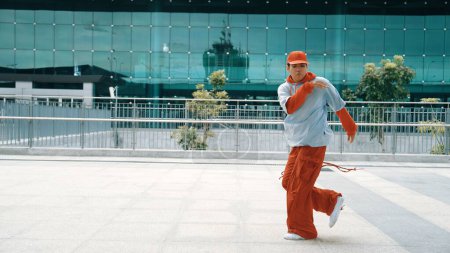 Photo for Skilled dancer moving energetic footstep while perform street dance. Professional hipster wearing stylish cloth while pose at camera. Freestyle dance. Modern lifestyle. Outdoor sport 2024. Sprightly. - Royalty Free Image