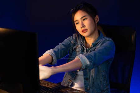 Photo for Young beautiful Asian businesswoman taking break with stretching body with ache symptom for relaxing muscle after finishing overworked load report at neon light modern office at night time. Stratagem. - Royalty Free Image